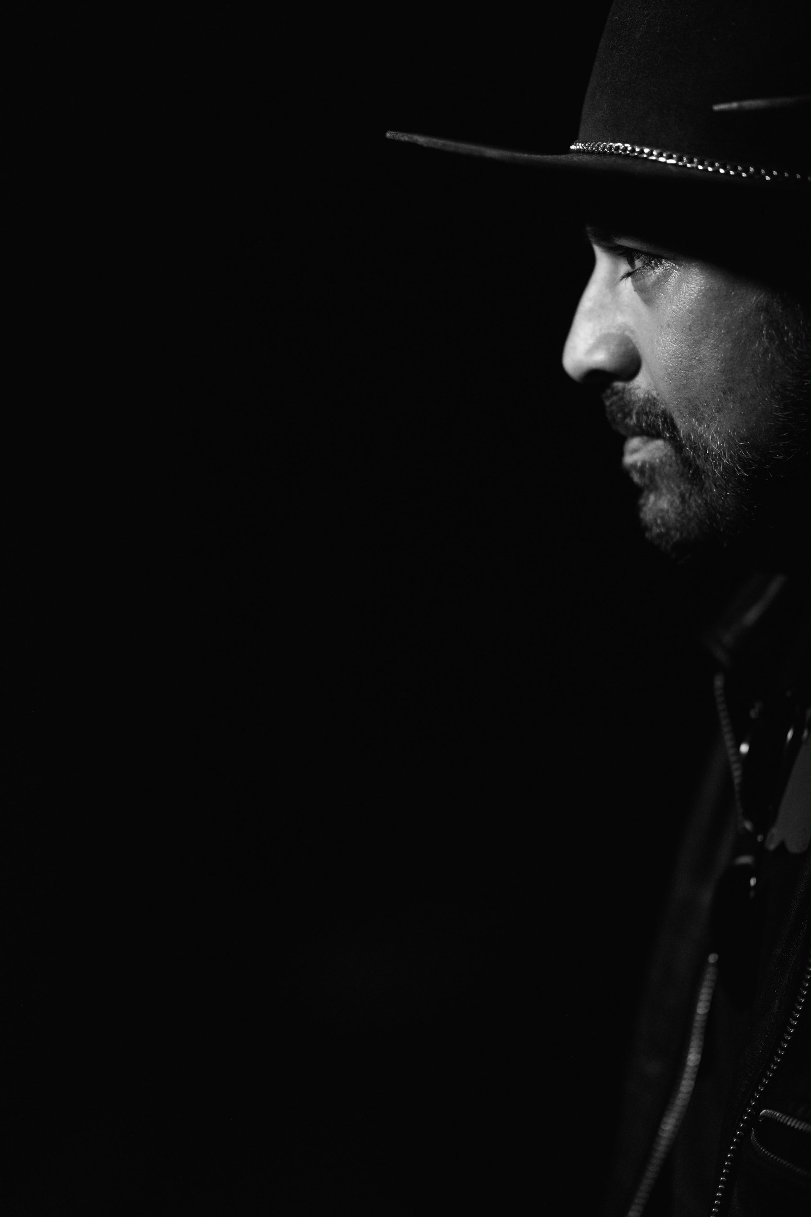 Frankie Owls in a black hat, photographed in dramatic black and white